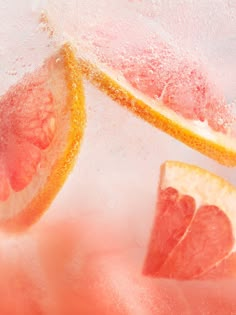 two grapefruits cut in half with water splashing on them