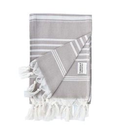 the grey and white towel is folded on top of each other, with fringes