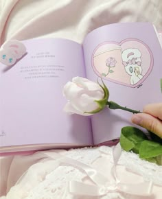 a person is holding a flower in front of an open book