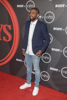 a man standing on a red carpet with his hands in his pockets and looking to the side