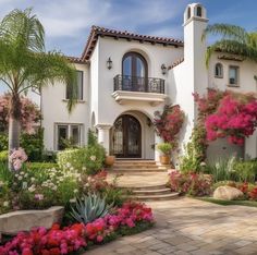 a house with lots of flowers in front of it and stairs leading up to the door