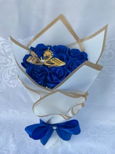 a bouquet of blue roses with a gold butterfly on the top and ribbon around it