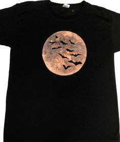 a black t - shirt with bats flying over the moon