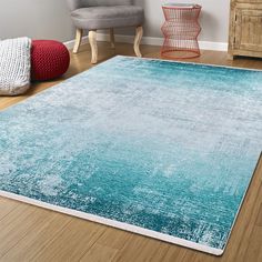 a blue rug in a living room next to a gray chair and wooden flooring