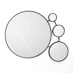 a round mirror sitting on top of a white wall next to two circular mirrors with circles around it