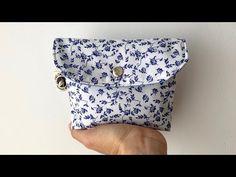 a hand holding a blue and white flowered purse