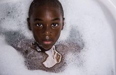 a young boy in a bathtub with bubbles around him