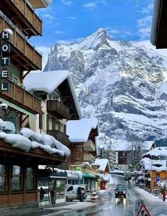 the mountains are covered in snow as people walk down the street