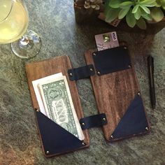 two wallets with money and pen on a table next to a glass of wine