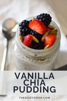 a jar filled with chia pudding topped with berries and almonds next to a spoon