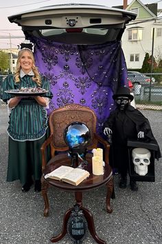 a woman standing in front of a car holding a tray with halloween decorations on it