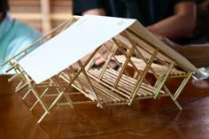 a model of a house sitting on top of a wooden table next to a man