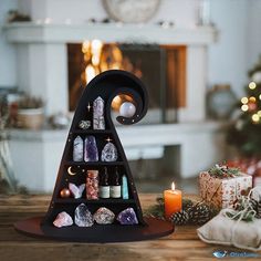 a christmas tree made out of bottles and rocks on a wooden table next to a lit candle