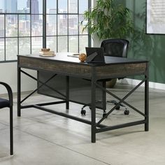 an office desk with a laptop on it in front of a large window and potted plant