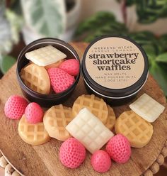 some waffles are sitting on top of a wooden plate with pink and white frosting