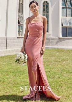 a woman in a long pink dress standing on the grass with her hand in her pocket