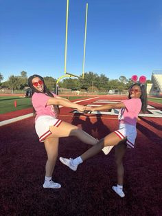 two girls in pink shirts and white shorts are playing with a baseball bat on the field