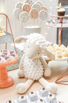 a stuffed animal sitting on top of a table next to cupcakes and cakes