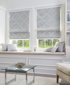 a living room filled with white furniture and windows covered in roman blind shades on the windowsill