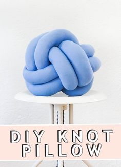 a blue knot sitting on top of a white table next to a sign that says diy knot pillow