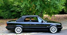 a black convertible car parked in front of a tree