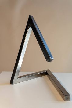 a metal triangle sculpture sitting on top of a white table