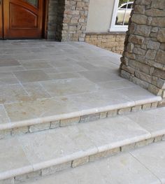 a dog is sitting on the front steps of a house that has stone steps leading up to it