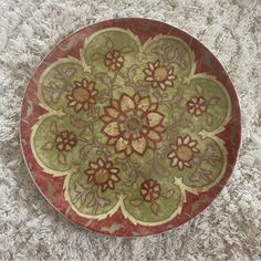 a red and green plate sitting on top of a white carpet next to a rug