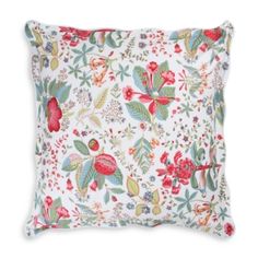 a white pillow with red and green flowers on the front, sitting on a white surface