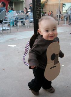 a young child holding onto a cardboard guitar