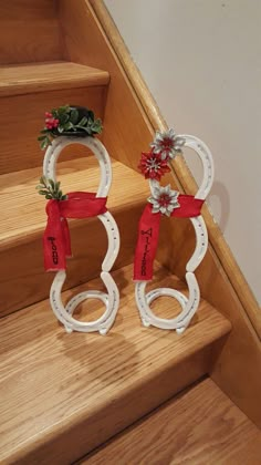 two christmas decorations sitting on top of a wooden stair case next to a banister