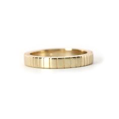 a yellow gold wedding ring with thin lines on the outside, and a flat surface