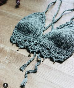 a crocheted bra with tassels is laying on a wooden floor next to other items