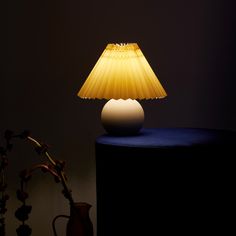 a yellow lamp sitting on top of a table next to a vase