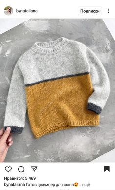 someone is holding their hand up to the sweater on the table, which has been made from an old sweater