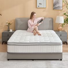 a woman sitting on top of a bed reading a book