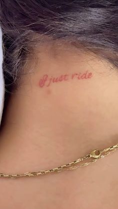 the back of a woman's neck with a tattoo saying just ride