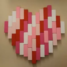 a heart made out of pink, white and red squares on a beige wall in the shape of a rectangle