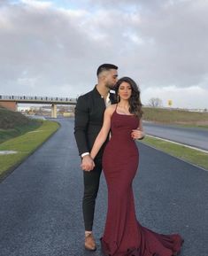 a man and woman are standing in the middle of an empty road, holding hands