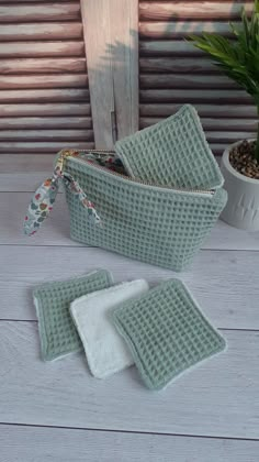 three pieces of green fabric sitting on top of a wooden table next to a potted plant