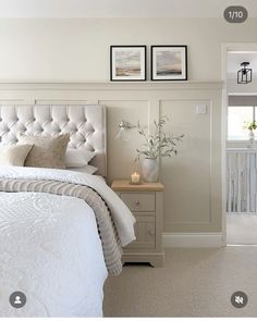 a white bed sitting in a bedroom next to two pictures on the wall above it