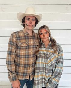 a man and woman wearing cowboy hats pose for a photo in front of a white wall