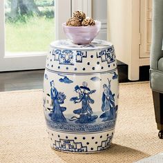 a blue and white vase sitting on top of a rug in front of a window