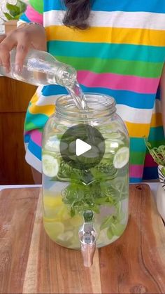 a woman pouring water into a jar filled with vegetables