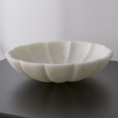 a white bowl sitting on top of a black table next to a wall and window