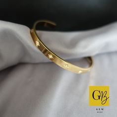 This is an exquisite gold cuff bracelet, which has 10 x cubic zirconia stars that are placed across the bracelet. This bracelet is meticulously crafted using high-quality stainless steel, ensuring durability and long-lasting shine. The gold plating adds a touch of luxury, making this piece a standout accessory for any occasion. When it comes to comfort and wearability, this bracelet excels. Made with nickel-free materials, it is suitable for those with sensitive skin and allergies. The gold plat Gold Celestial Bracelet For Gift, Celestial Gold Bracelet As Gift, Celestial Gold Bracelet For Gift, Celestial Style Gold Bracelet As Gift, Gold Star-shaped Bracelet As Gift, Luxury Gold Star Bracelets, Gold Star-shaped Celestial Bracelets, Modern Gold Cuff Bracelet With Cubic Zirconia, Modern Gold Cubic Zirconia Cuff Bracelet