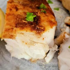 a piece of fish sitting on top of a table next to a slice of lemon