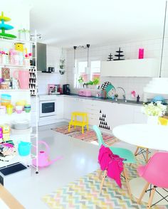 a kitchen filled with lots of colorful furniture and decor on top of a white floor