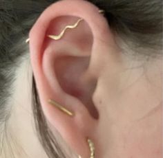 a woman's ear is shown with two thin gold bars sticking out of it