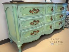 an antique dresser painted in green with gold leaf decorations on the top and bottom drawers